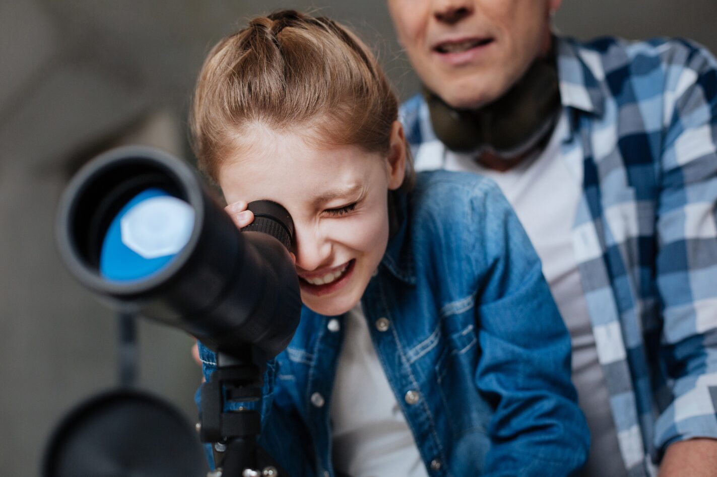 Homeschool dad helping his daughter learn astronomy by looking through a telescope